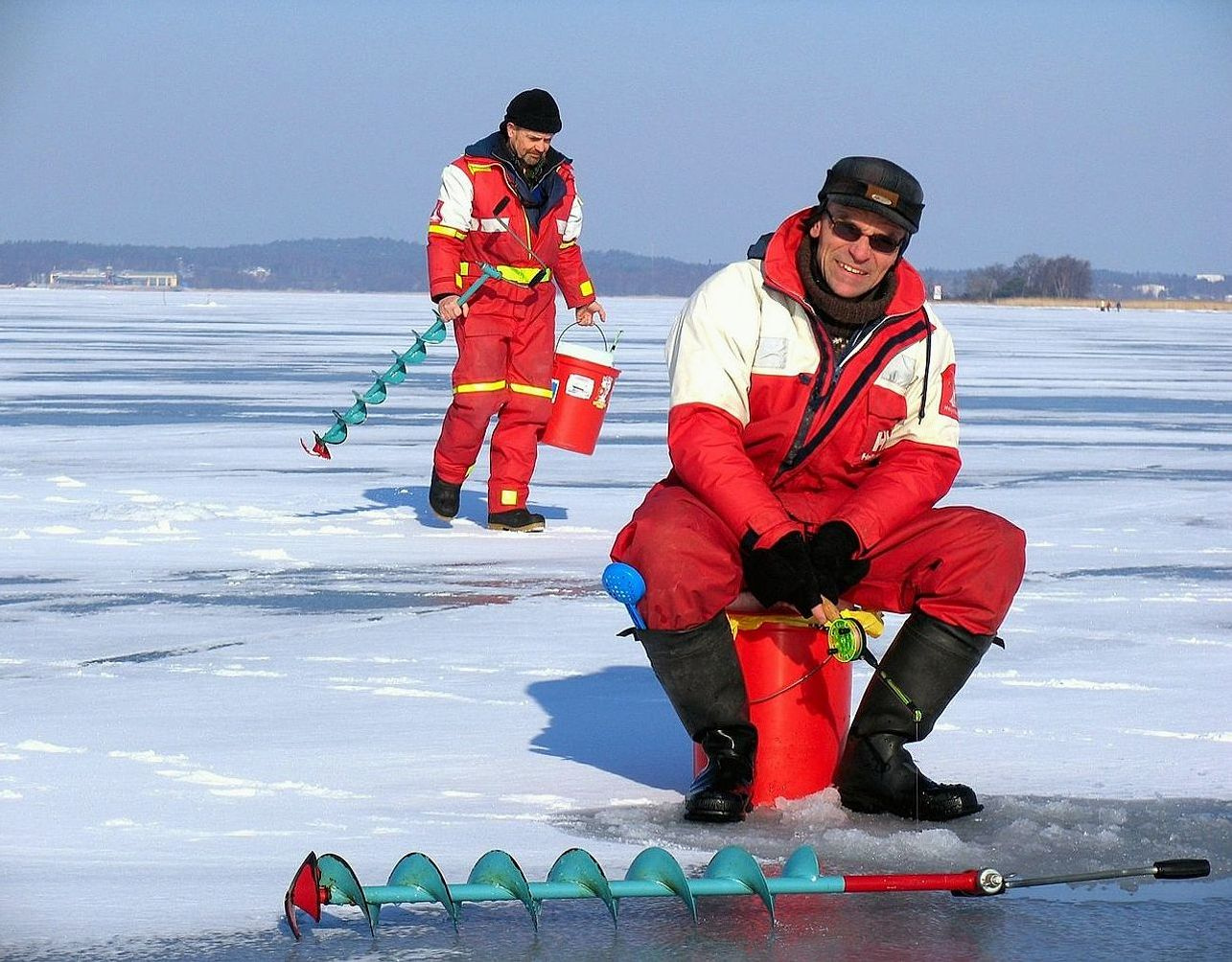 A workbench displaying ice augers, winter rods, and thermal gear laid out for inspection