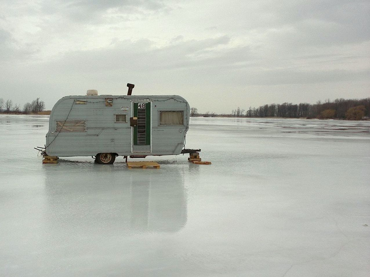 Ice fishing auger cutting through thick winter ice